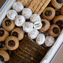 Load image into Gallery viewer, Assorted cookies including round cookies with dark centers and powdered sugar-coated cookies in a box.
